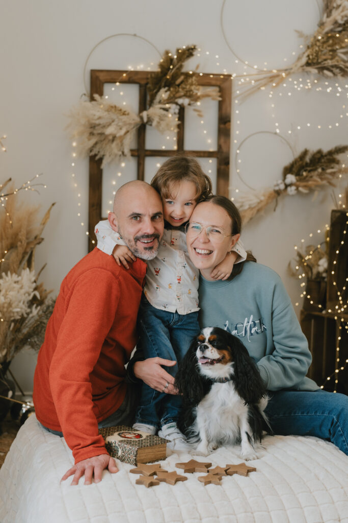 Servizio fotografico di Natale con il cane: famiglia sul set bianco e oro